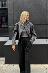 a lady wears a gray boxy coat with black pants